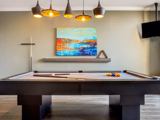Game room with pool table and lounge seating in Apex Apartments, perfect for relaxation and socializing in a luxury setting