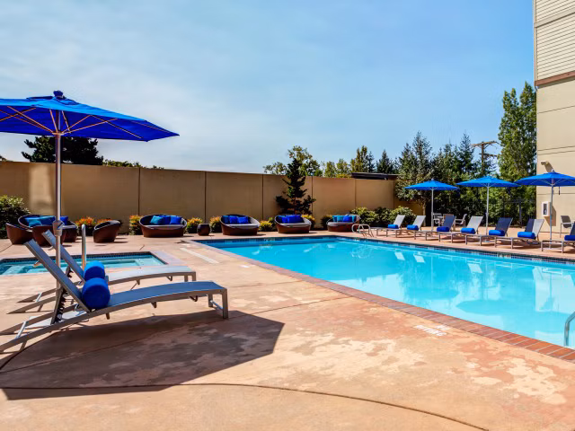 Luxurious pool with sun loungers at Apex Apartments, perfect for relaxation and leisure activities