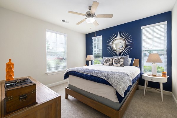 Bedroom with modern furnishings and large window at Parkside Place Apartments, a luxury property by Greystar