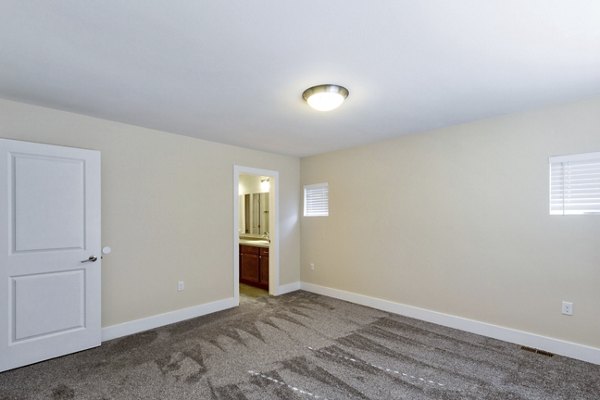 Bedroom with cozy dÃ©cor and large windows at Creekstone Twin Homes luxury apartments