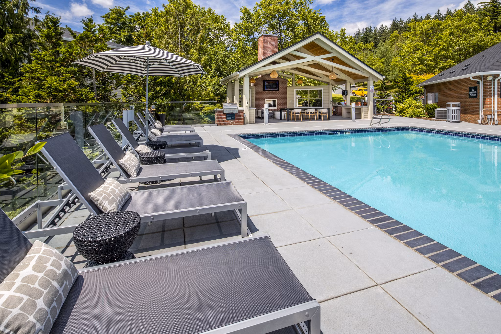 Inviting outdoor pool with surrounding lounge chairs at Arbor Heights Apartments, ideal for relaxation and recreation