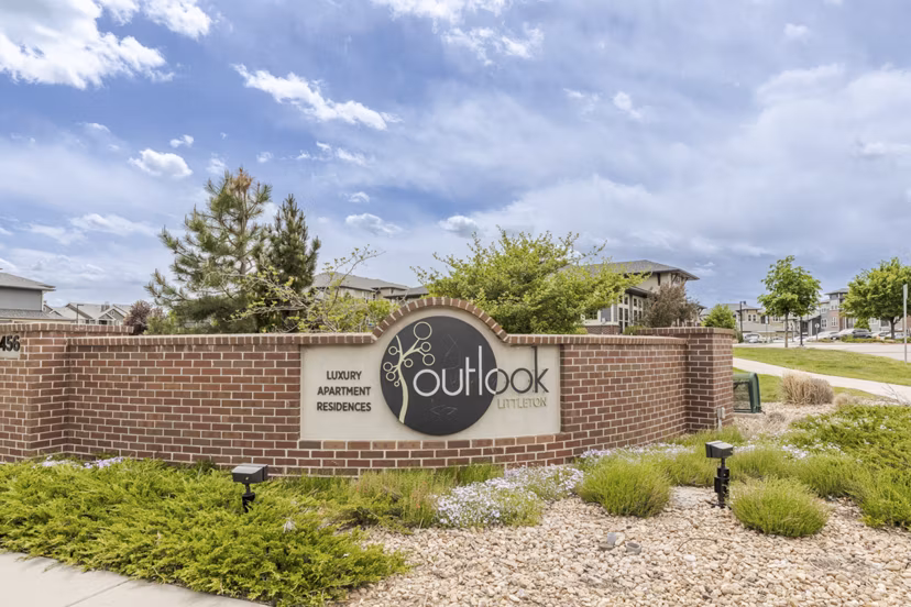 Outlook Littleton: Elegant brick sign for luxury apartments surrounded by landscaped greenery