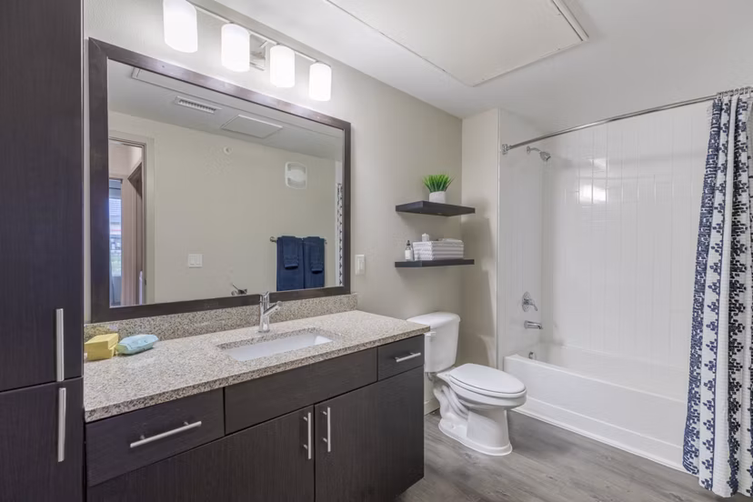 Bathroom with sleek fixtures and large mirror at Outlook Littleton Apartments, showcasing modern design for luxury living