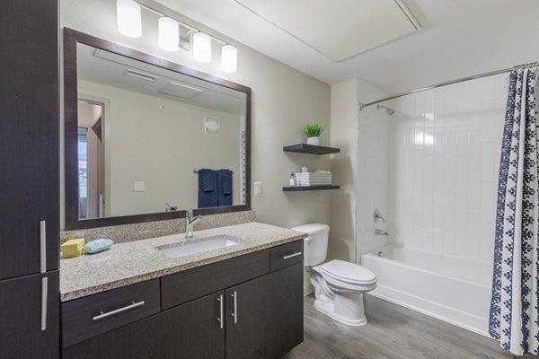 Bathroom with sleek fixtures and large mirror at Outlook Littleton Apartments, showcasing modern design for luxury living