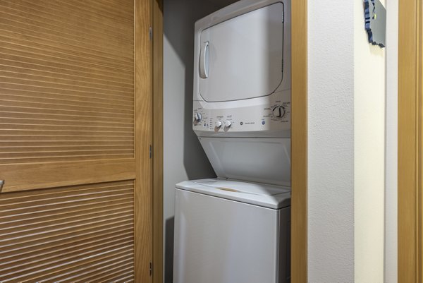 Laundry room with modern appliances and ample storage at The Luke Apartments