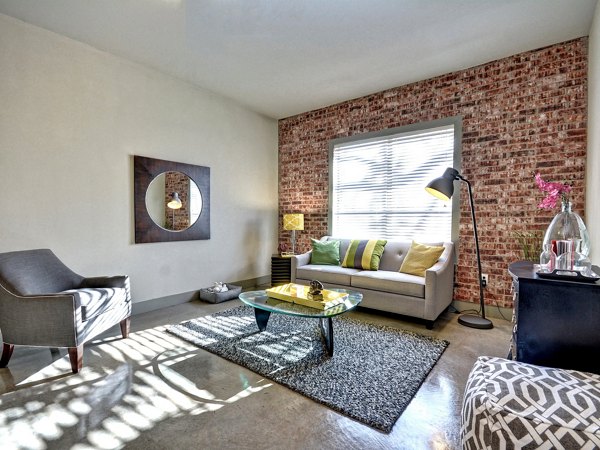 Modern living room with a sofa, armchair, and brick accent wall in luxury apartments