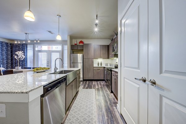 Modern kitchen with granite countertops and stainless steel appliances at Boardwalk Research Luxury Apartments
