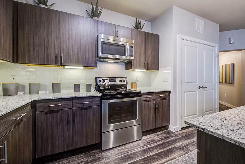 Modern kitchen with stainless steel appliances at Boardwalk Research Luxury Apartments, featuring sleek cabinets and granite countertops