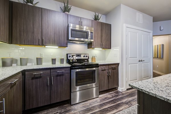 Modern kitchen with stainless steel appliances at Boardwalk Research Luxury Apartments, featuring sleek cabinets and granite countertops