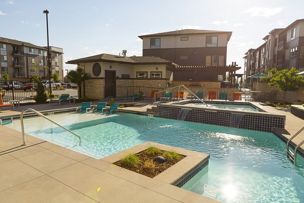 Resort-style pool area at Outlook Golden Ridge Apartments featuring lounge chairs and lush landscaping