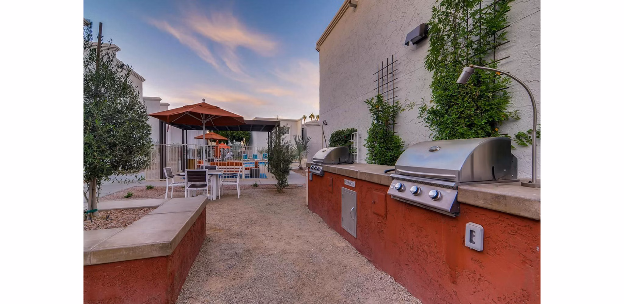 Outdoor grill area surrounded by lush greenery at The Cortesian Apartments