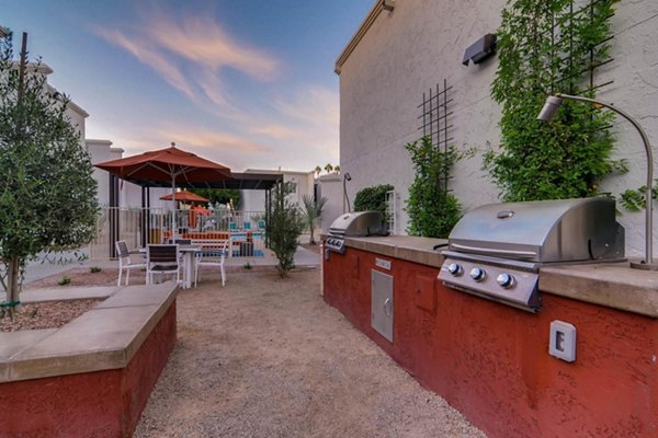 Outdoor grill area surrounded by lush greenery at The Cortesian Apartments