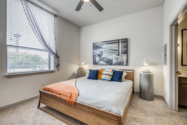 Cozy bedroom featuring minimalist decor and natural light in Agave Apartments
