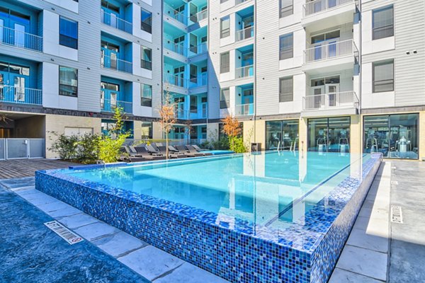 Rooftop pool with lounge chairs at Agave Apartments, offering luxury amenities and city views in a tranquil setting