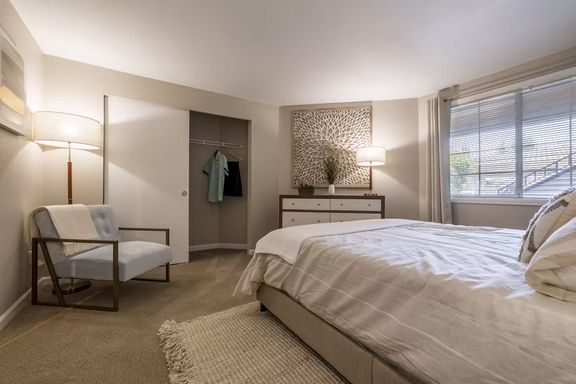 Cozy bedroom with modern decor at The Seasons Apartments, featuring luxurious bedding and ample natural light for ultimate comfort