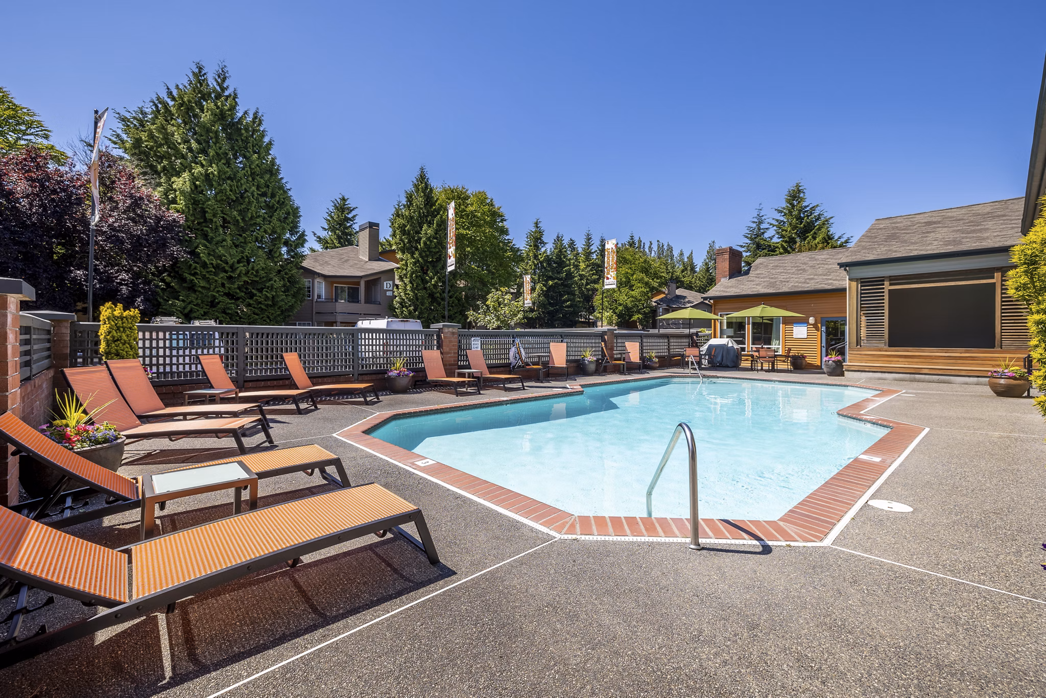 Sunlit outdoor pool at The Seasons Apartments with surrounding lounge chairs