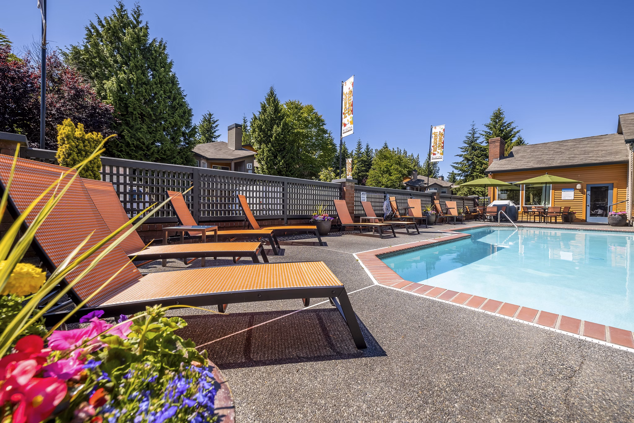 Inviting pool surrounded by lush landscaping at The Seasons Apartments, offering a serene retreat for residents
