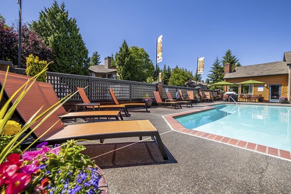 Inviting pool surrounded by lush landscaping at The Seasons Apartments, offering a serene retreat for residents