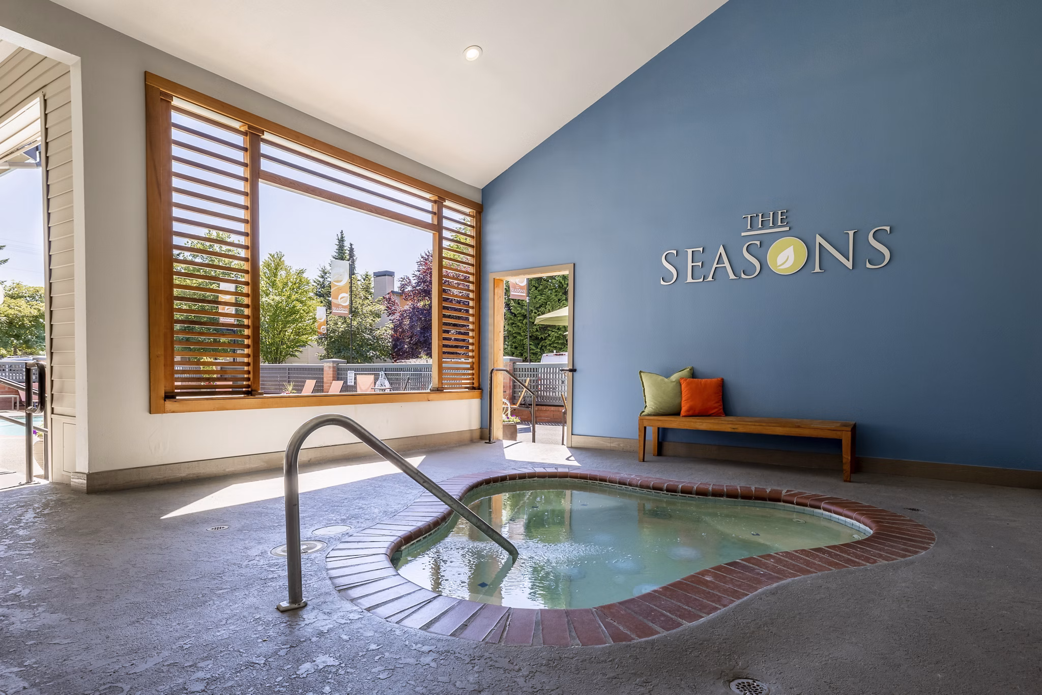 Outdoor swimming pool with lounge chairs at The Seasons Apartments, offering luxury relaxation and leisure options for residents