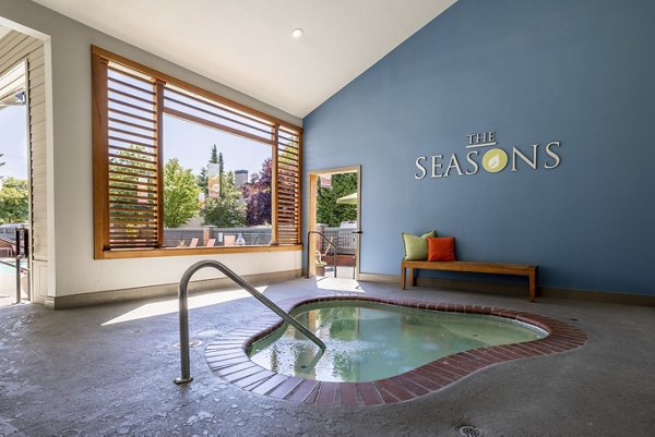 Outdoor swimming pool with lounge chairs at The Seasons Apartments, offering luxury relaxation and leisure options for residents