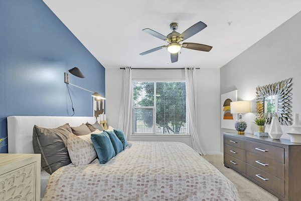 Cozy bedroom with modern decor at Oak & Ellum Apartments featuring a plush bed and ambient lighting