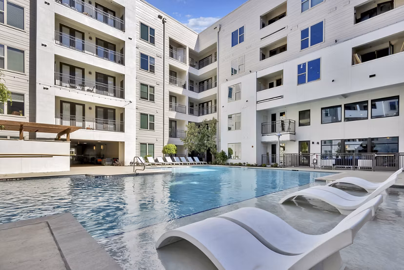 Luxurious outdoor pool at Oak & Ellum Apartments with modern lounge chairs and landscaped surroundings, perfect for relaxation and leisure