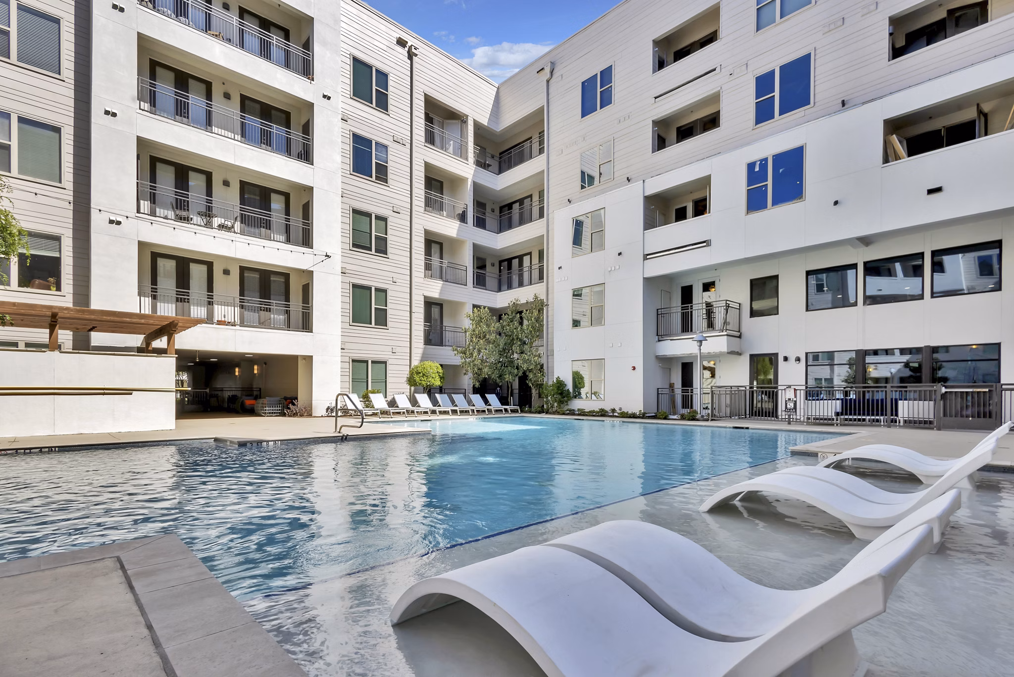 Luxurious outdoor pool at Oak & Ellum Apartments with modern lounge chairs and landscaped surroundings, perfect for relaxation and leisure