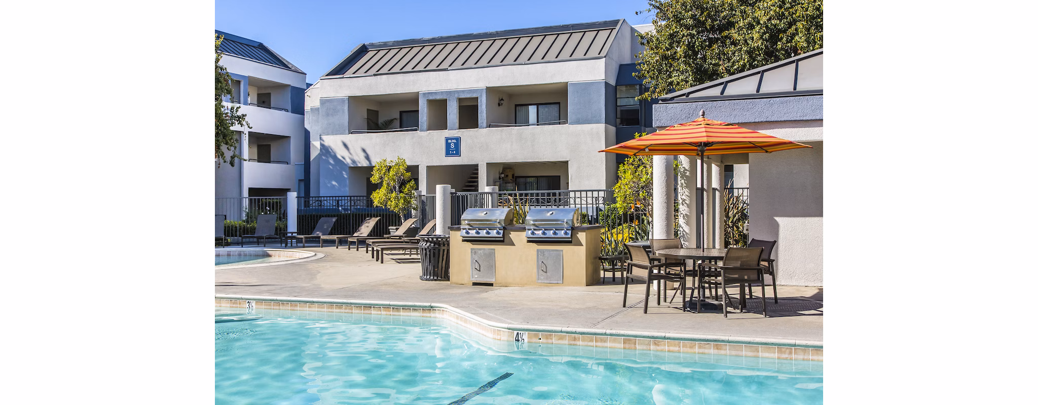 Luxurious pool at Avana Rancho Cucamonga Apartments featuring sun loungers and palm trees, perfect for relaxing in the California sun