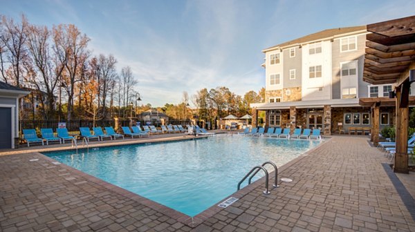 Resort-style pool area with lounge chairs at Element Ballantyne Apartments in Charlotte