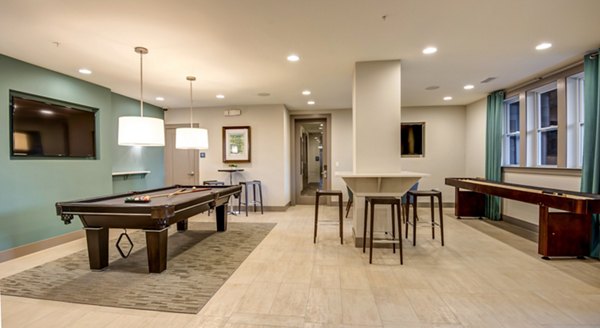 Recreation room with a pool table, shuffleboard, and high-top tables in luxury apartments