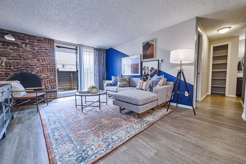Living room featuring cozy fireplace and large windows at The Lodge Apartment Homes, luxury living by Greystar