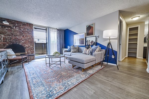 Living room featuring cozy fireplace and large windows at The Lodge Apartment Homes, luxury living by Greystar