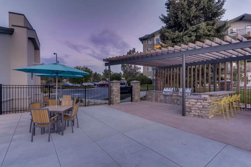 Outdoor grill area at The Lodge Apartment Homes with picnic tables and BBQ facilities
