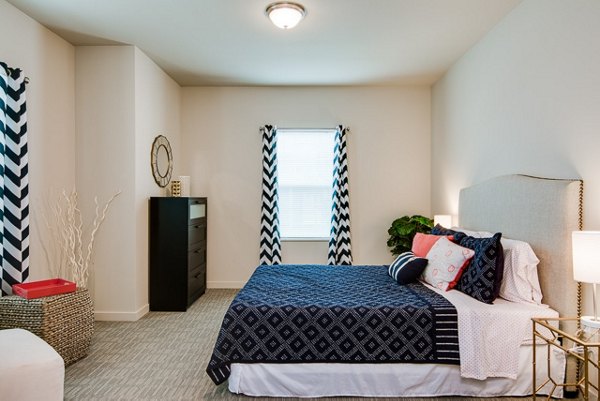 Cozy bedroom featuring elegant furniture and large windows in The Bailey at Amazon Creek Apartments