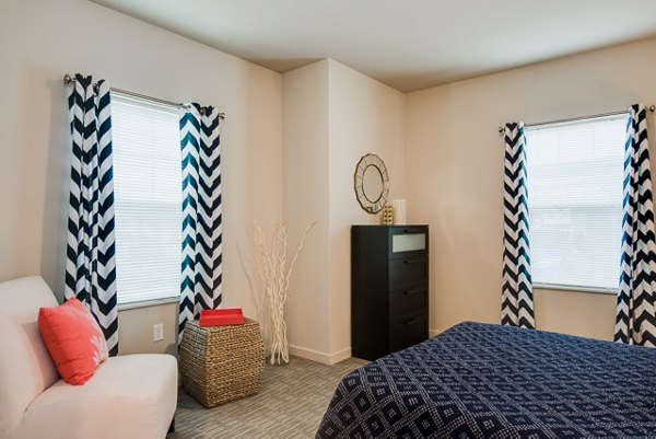 Bedroom with modern furnishings and large windows at The Bailey at Amazon Creek Apartments