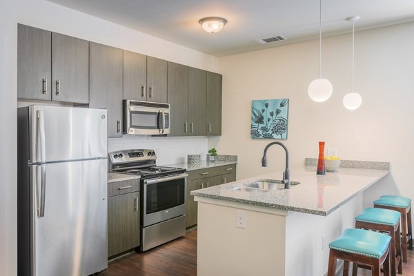 Modern kitchen with stainless steel appliances and granite countertops in M Station Apartments floor plan