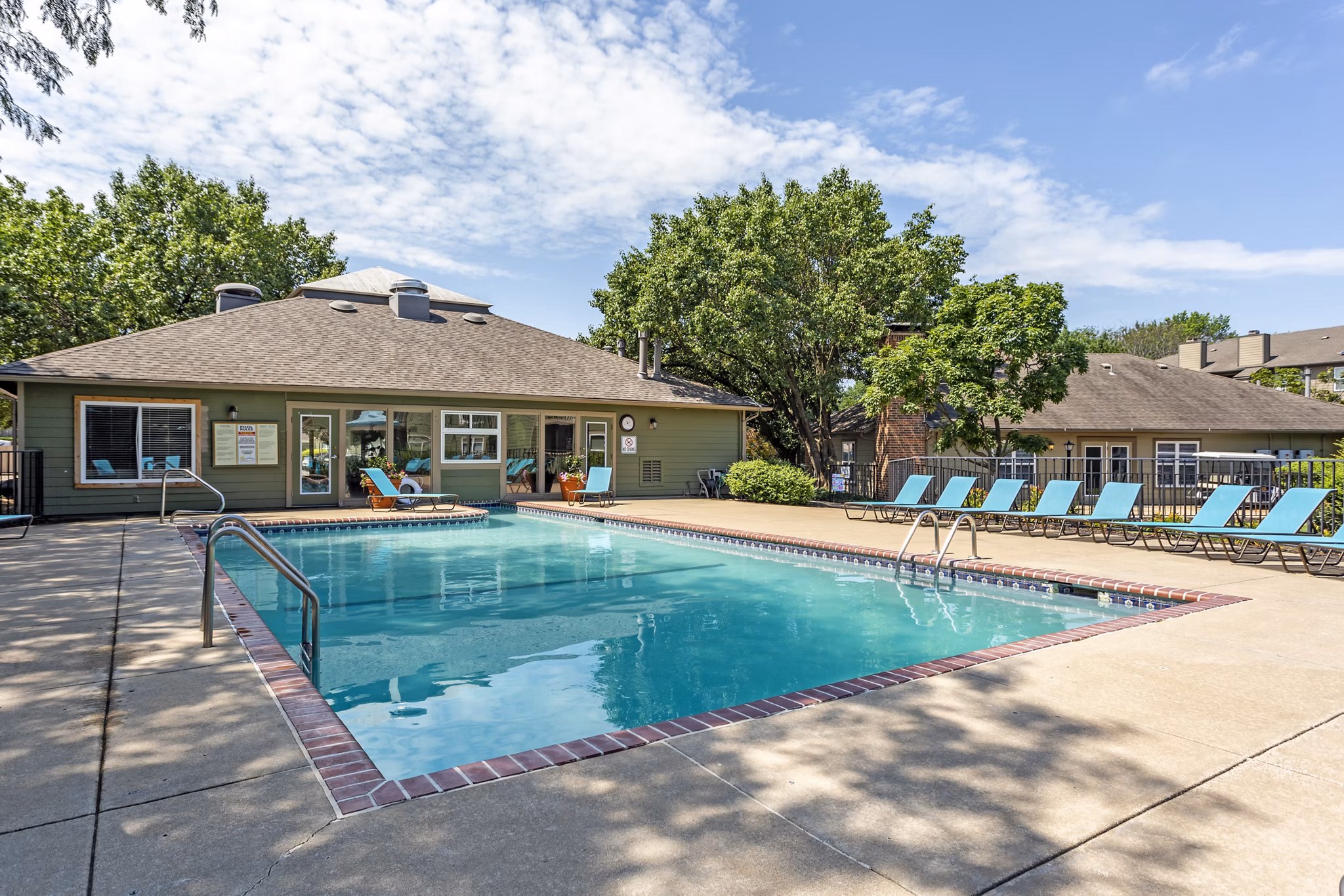 Tranquil swimming pool at Sun River Village Apartments featuring surrounding lush greenery