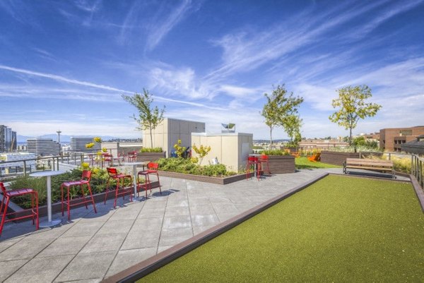Patio with modern furniture at Cue Apartments offering stunning city views