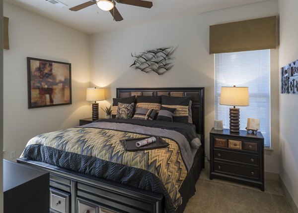 Cozy bedroom with stylish decor and large windows at Avana on the Platte Apartments, offering modern comfort in a luxury setting