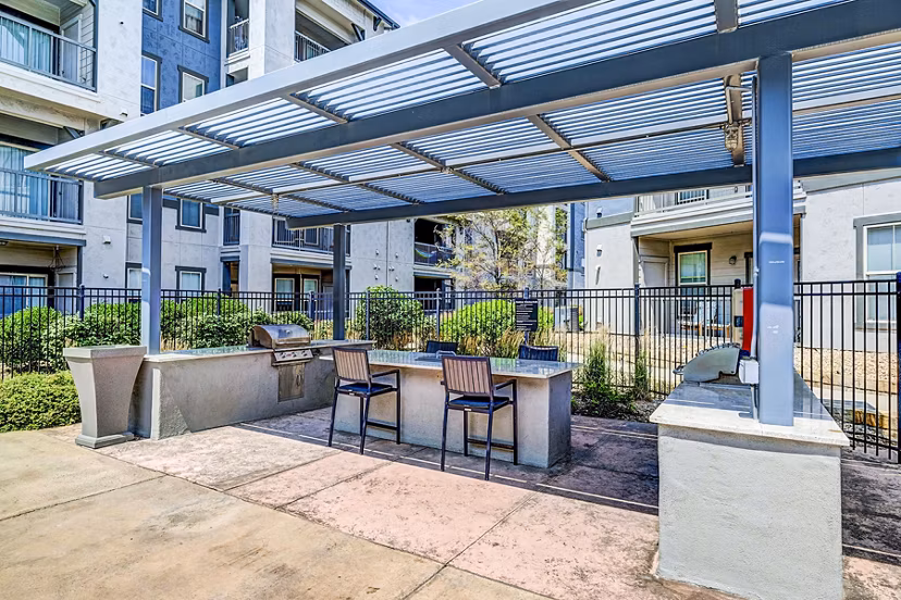 Outdoor grill area with modern seating at Avana on the Platte Apartments, ideal for social gatherings and dining in a serene atmosphere