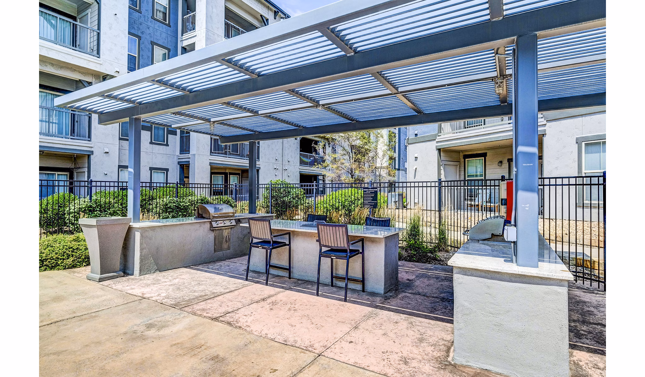 Outdoor grill area with modern seating at Avana on the Platte Apartments, ideal for social gatherings and dining in a serene atmosphere