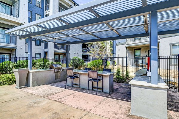 Outdoor grill area with modern seating at Avana on the Platte Apartments, ideal for social gatherings and dining in a serene atmosphere