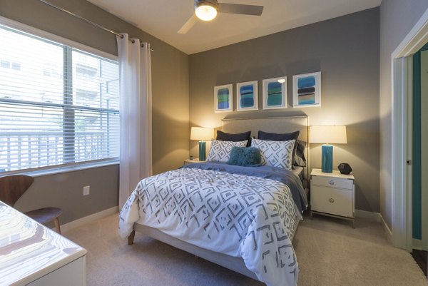 Cozy bedroom with large windows at Junction Six Forks Apartments, offering luxury living spaces