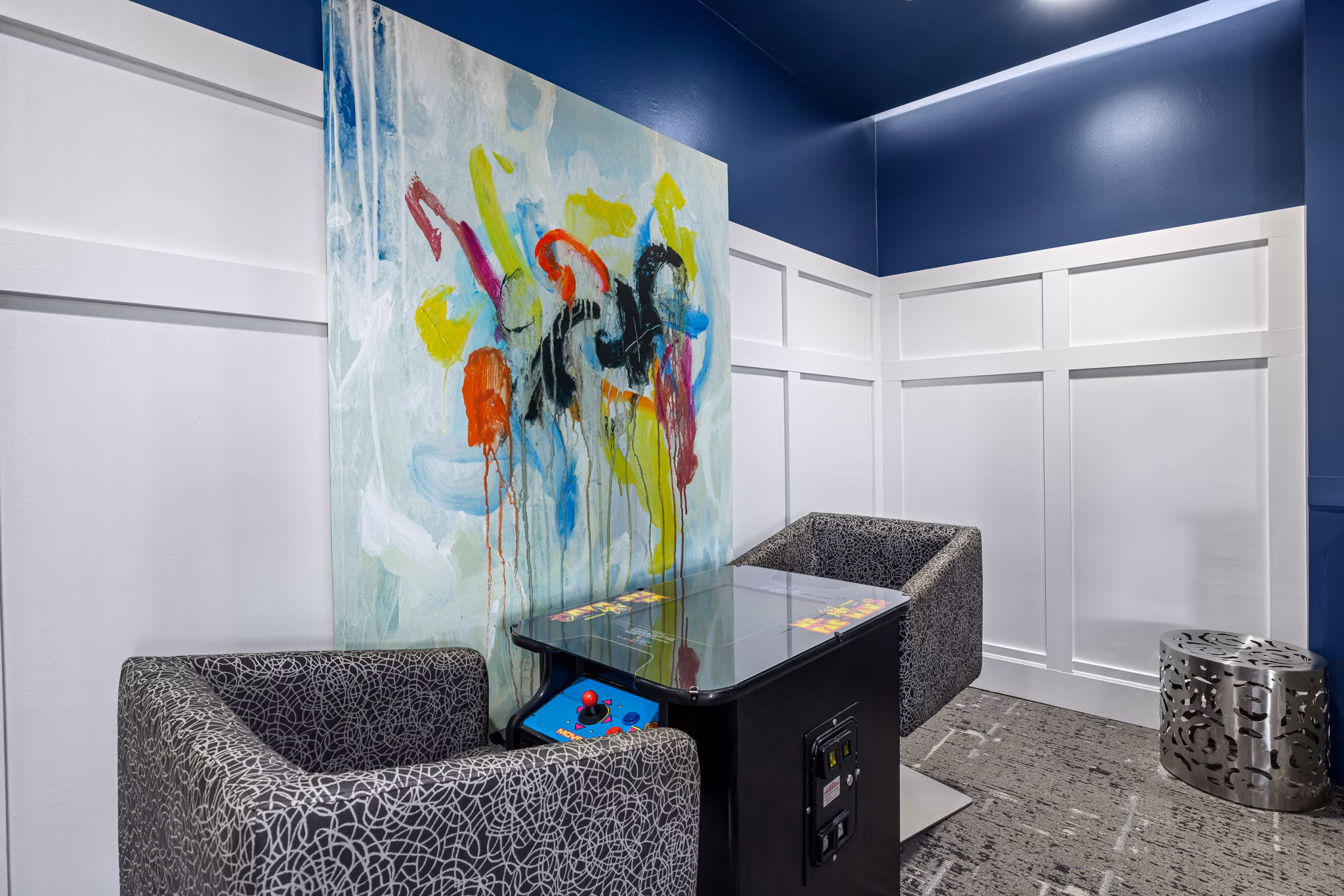 Cozy game nook featuring patterned chairs and an abstract painting in luxury apartments