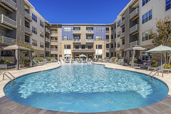 Resort-style pool with lounge seating at Junction Six Forks Apartments in Raleigh, enhancing luxury living experience