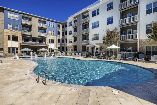 Modern pool area with lounge chairs and umbrellas at Junction Six Forks Apartments in Raleigh, offering a luxury relaxation space for residents