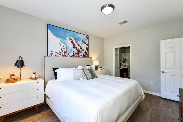 Bedroom with modern decor and large windows in Avana Ridenour Apartments