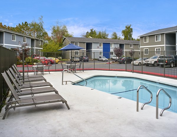 Luxury outdoor pool area at Irwin Park Apartments with seating and lush landscaping, perfect for relaxation and entertaining