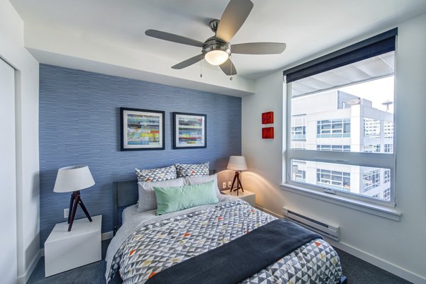 Bedroom with geometric bedding, blue accent wall, and closet at Radius Apartments, a Greystar luxury apartment community in the heart of the city