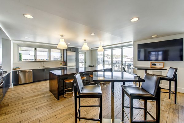 Modern lounge area with sofas, tables, and large TV at Radius Apartments, Greystar luxury property in vibrant location